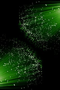 Close up capturing the ends of many illuminated green fibre optic light strands arranged against black.