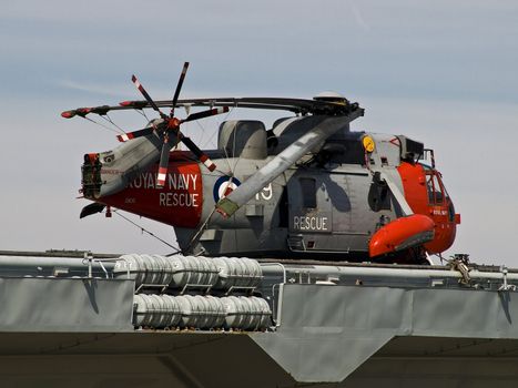 A shiny Royal Navy helicopter at rest on the Ark Royal at Liverpool