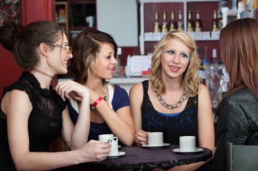 Four cute teenaged girls talk at a restaurant over coffee