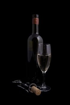 White wine bottle and glass with corkscrew over black