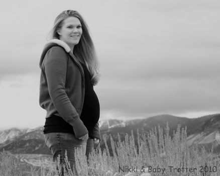 A happy/jolly pregnant girl standing in nature.