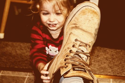 A young girl taking of her fathers boot after a long hard days work.