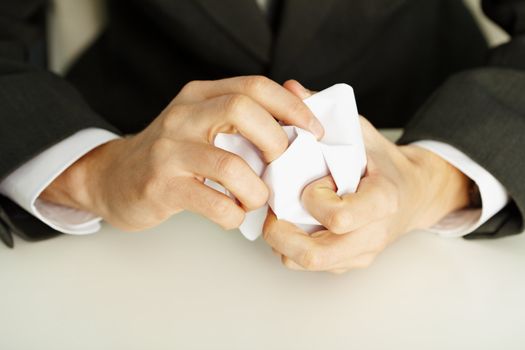 Man's hands crumpling a white paper close up