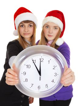 Two girls in New Year's caps with clock in hands on white