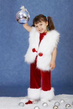 The little girl in a New Year costume holding a glass ball on blue