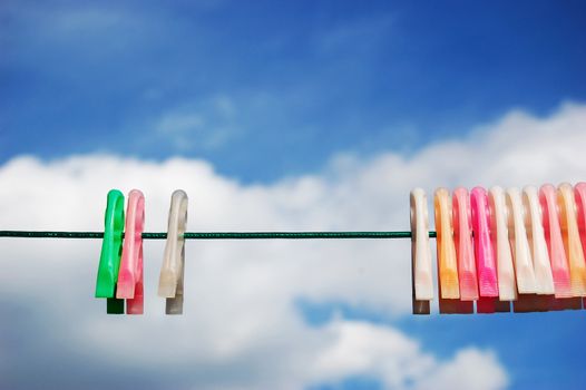 Colorful clothespins over blue sky