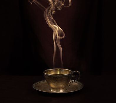 Hot coffee in gold antique cup, and smoke above