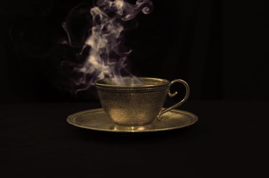 Hot coffee in gold antique cup, and smoke above