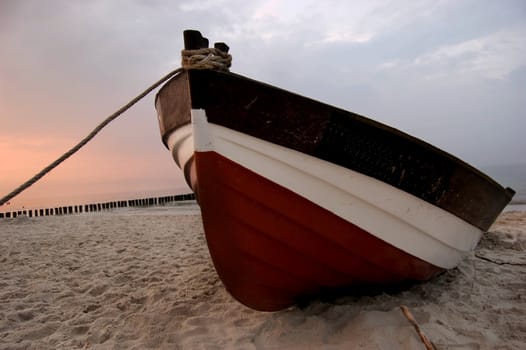 Old fishboat on sandy beach. Beautiful sunset - Baltic Sea in Poland
