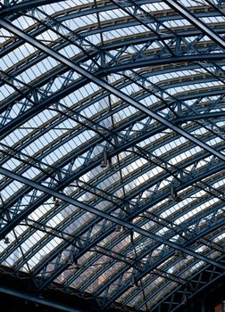 Clock tower of St Pancras station visible through the ornate glass roof of the entrance hall of the building