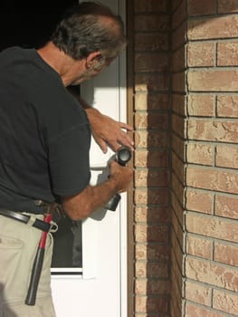A man is remodelling his house, and installing a white door with glass in the middle to his front entrance.
