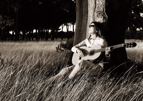 Woman playing her guitar at the sunset (Toned in PS)