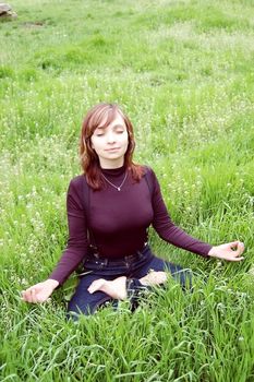 Girl making yoga among green grass, meditating