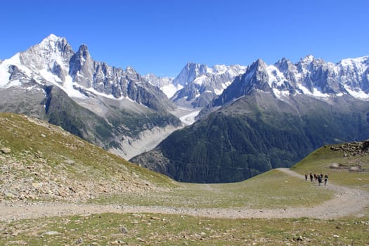 View of the Mont-Blanc massif from a small path in the mountain with few walkers, France, by beautiful weather