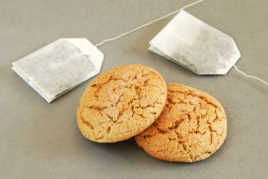 two fresh appetizing oatmeal cookies with tee bags over gray background