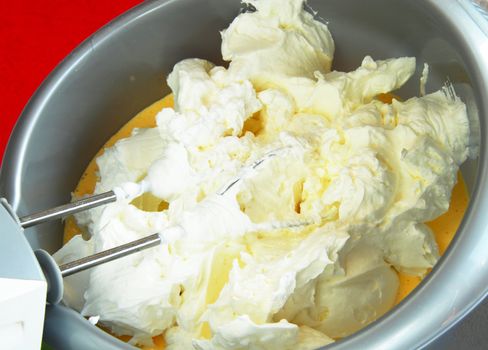 mixer whisks with white cream whipped over silver bowl