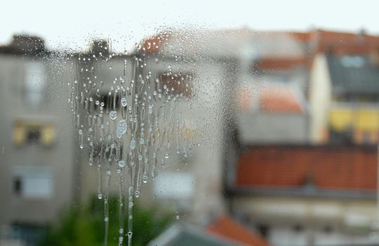 cleaning spray flowing down on window glass surface