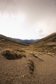 The view down a valley from Armstrong Saddle in the Ruahine Ranges, North Island, New Zealand. Snow capped Mount Taranaki can be seen in the distance.