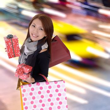Happy shopping woman in modern colorful city night with cars motion blurred.