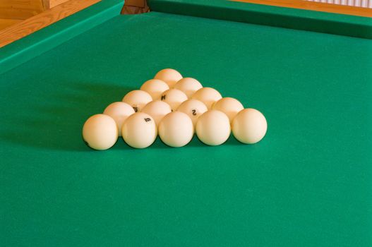Triangle of balls for Russian billiards on a table with green baize.