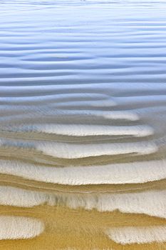 Wet sand texture on ocean shore formed by gentle waves