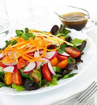 Plate of healthy green garden salad with fresh vegetables served with balsamic dressing