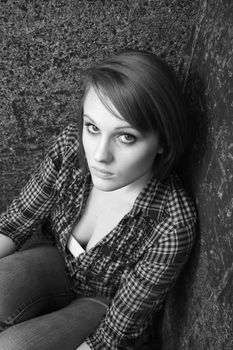 A beautiful young woman sitting in a corner, black and white