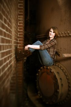 A beautiful young woman sitting on an iron wall