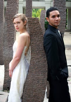 A bride and a groom leaning against a rock