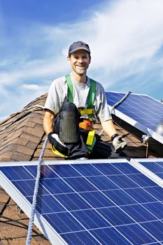 Man installing alternative energy photovoltaic solar panels on roof