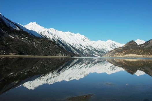 Landscape of snow-capped mountains with a mirror in the lake