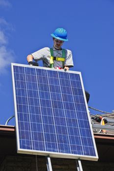 Man installing alternative energy photovoltaic solar panels on roof