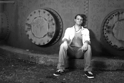 A young man resting against an iron wall