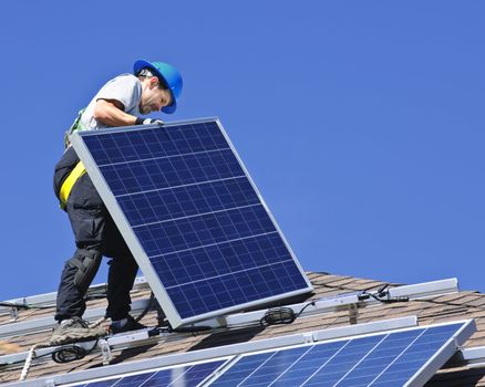 Man installing alternative energy photovoltaic solar panels on roof