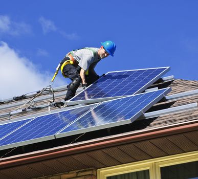 Man installing alternative energy photovoltaic solar panels on roof