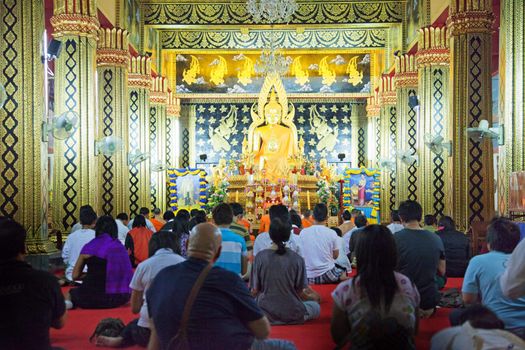 Praying people in the colorful temples are visible from behind
