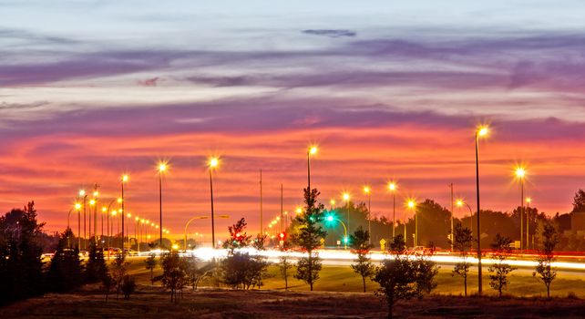 A photograph highway one at night with street lights and light streak from the headlights and taillights of passing cars