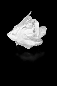 A piece of discarded paper isolated on black