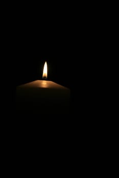 a white burning candle with black background