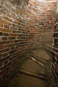 Old staircase in a tight corridor with old brick walls