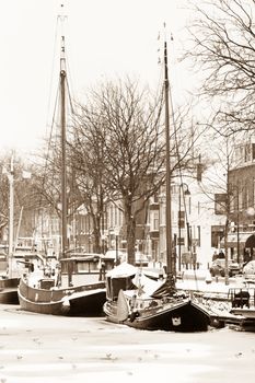 Fishingboats in the harbor with winter  ice and snow - old fashioned sepia image