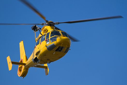 Flying yellow helicopter with blue sky background