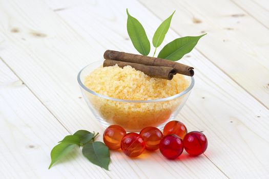 bowl of orange bath salt, cinnamon sticks and oil pearls