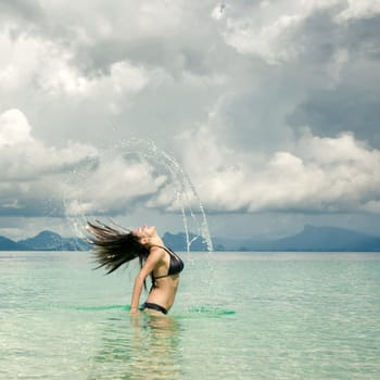 Splash of water made by hair of young woman swimming in the sea