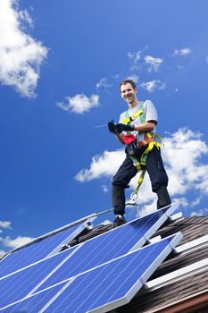 Worker installing alternative energy photovoltaic solar panels on roof