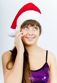 happy smiling girl with Santa hat with a phone on a light background. Studio photography
