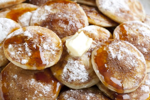 Dutch mini pancakes, or poffertjes, with butter, syrup and powdered sugar.  background.