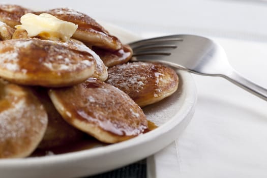 Dutch mini pancakes, or poffertjes, with butter, syrup and powdered sugar.