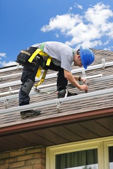 Man installing rails for solar panels on residential house roof