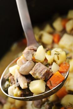 Hearty beef and potatoes stew with vegetables served with ladle